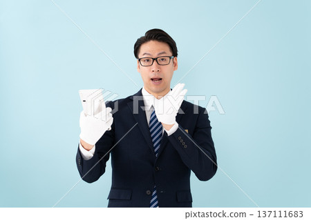 A man wearing white gloves holding a calculator is surprised 137111683