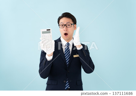 一名戴著白手套、手持計算器的男子感到驚訝 137111686