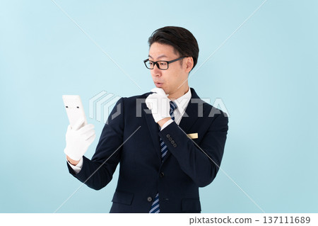 A man wearing white gloves holding a calculator is surprised A man wearing white gloves holding a calculator is surprised 137111689