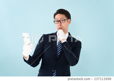 A man wearing white gloves holding a calculator is surprised 137111690