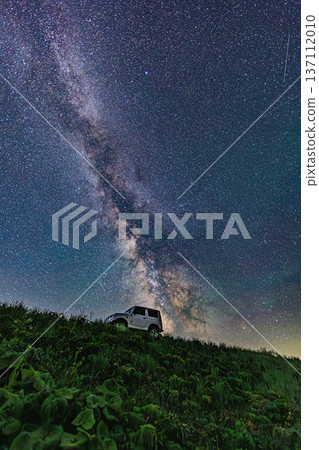 A four-wheel drive vehicle under the Milky Way. A starry night outdoor scene. 137112010