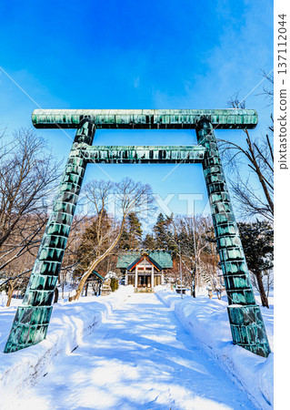 The torii gate and main building of Koshimizu Shrine stand out against the blue sky and snowy scenery of Hokkaido. The torii gate and main building of Koshimizu Shrine stand out against the blue sky and snowy scenery of Hokkaido. 137112044