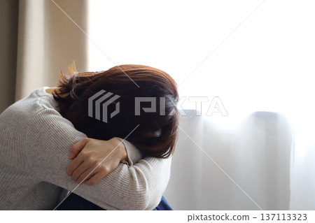憂鬱的女人將臉埋在臂彎裡 憂鬱的女人將臉埋在臂彎裡 137113323