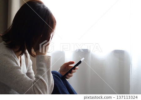 一位憂心忡忡的女性正看著她的智慧型手機 137113324