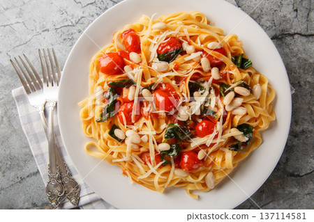 Italian tagliatelle pasta with white beans, cherry tomatoes, parmesan and spinach close-up in a plate. Horizontal top view Italian tagliatelle pasta with white beans, cherry tomatoes, parmesan and spinach close-up in a plate. Horizontal top view 137114581