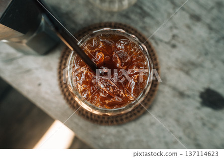 Refreshing iced black coffee in a glass with moka pot on a rustic wooden table. Refreshing iced black coffee in a glass with moka pot on a rustic wooden table. 137114623