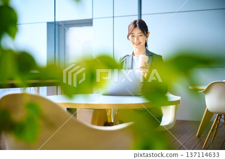 Businesswoman in a suit holding a smartphone / Office cafe Photo courtesy: Sky Perfect Tokyo Media Center Businesswoman in a suit holding a smartphone / Office cafe Photo courtesy: Sky Perfect Tokyo Media Center 137114633