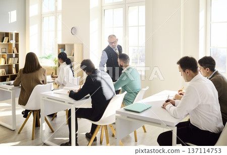 University instructor guiding adult learners in modern classroom training session University instructor guiding adult learners in modern classroom training session 137114753
