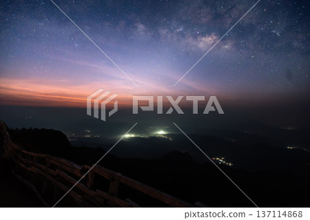 Beautiful twilight sky with stars over a mountain ridge trail and wooden fence at dawn. Beautiful twilight sky with stars over a mountain ridge trail and wooden fence at dawn. 137114868