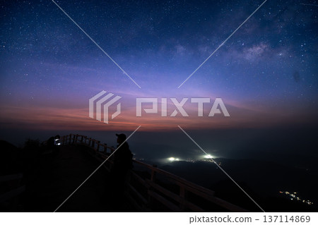 Beautiful twilight sky with stars over a mountain ridge trail and wooden fence at dawn. Beautiful twilight sky with stars over a mountain ridge trail and wooden fence at dawn. 137114869
