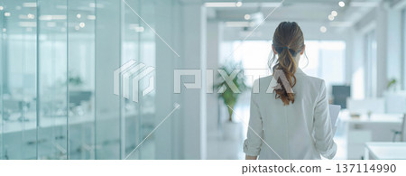 一位女商務人士在明亮的辦公室裡行走,鏡頭從背後拍攝。 一位女商務人士在明亮的辦公室裡行走,鏡頭從背後拍攝。 137114990