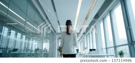 一位女商務人士在明亮的辦公室裡行走,鏡頭從背後拍攝。 一位女商務人士在明亮的辦公室裡行走,鏡頭從背後拍攝。 137114996