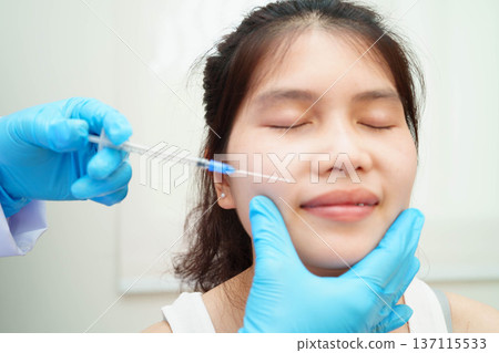 Asian woman receiving plastic surgery shape of nose performed on face. Asian woman receiving plastic surgery shape of nose performed on face. 137115533