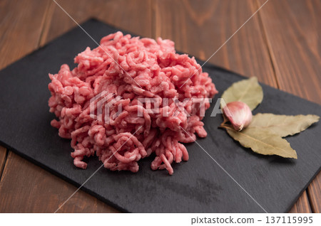 Fresh minced pork on black plate and wooden background. Fresh minced pork on black plate and wooden background. 137115995