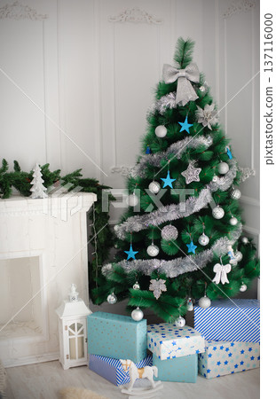 Room with a Christmas tree and a white fireplace by the fireplace 137116000
