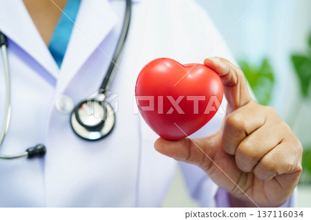 Asian woman doctor holding red heart for health in hospital. Asian woman doctor holding red heart for health in hospital. 137116034
