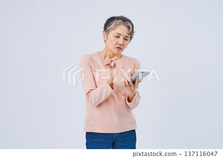 Senior woman with a troubled expression holding a smartphone 137116047