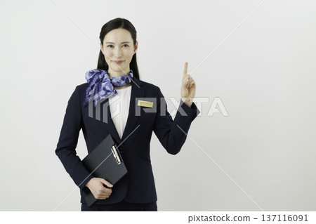 A smiling Japanese woman concierge wearing a navy blue suit, ribbon, and name tag posing as number one on a white background A smiling Japanese woman concierge wearing a navy blue suit, ribbon, and name tag posing as number one on a white background 137116091