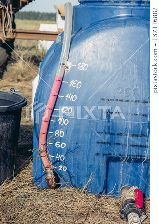 large blue plastic tank filled, agricultural mixing process, hoses connected for chemical transfer in sunny rural field, agriculture, irrigation, chemistry, fungicides 137116882