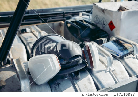 industrial respirator mask resting on metal canister at outdoor work site with heavy equipment background industrial safety scene concept of construction, manufacturing, occupational health 137116888