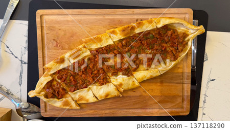 Fresh pide sliced on wooden board. Lunch meal, comfort food, Turkish cuisine tradition, dining moment and homemade baked serving. Fresh pide sliced on wooden board. Lunch meal, comfort food, Turkish cuisine tradition, dining moment and homemade baked serving. 137118290
