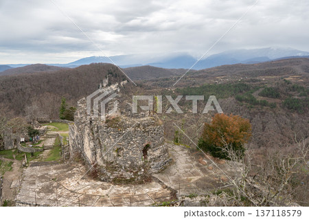 Anakopia fortress stone tower ruins with mountain panorama and distant snowfall over forest landscape in Abkhazia. Image supports travel marketing, adventure tourism promotion and heritage destination Anakopia fortress stone tower ruins with mountain panorama and distant snowfall over forest landscape in Abkhazia. Image supports travel marketing, adventure tourism promotion and heritage destination 137118579
