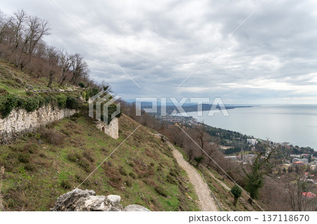 Anacopia fortress walls along hillside overlooking New Athos coastline and Black Sea in Abkhazia under cloudy sky, Historic architecture and coastal landscape suitable for tourism marketing 137118670