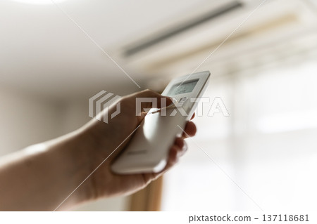 Hand to operate the remote control of the air conditioner Hand to operate the remote control of the air conditioner 137118681