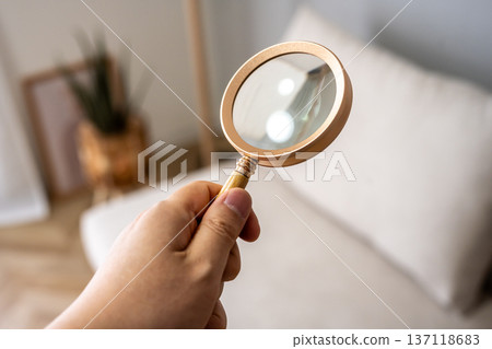 Hand examining the room with a magnifying glass Hand examining the room with a magnifying glass 137118683