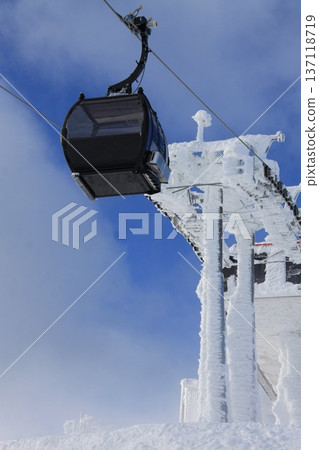 modern cable car ascending a frost-covered tower at a snowy mountain resort modern cable car ascending a frost-covered tower at a snowy mountain resort 137118719