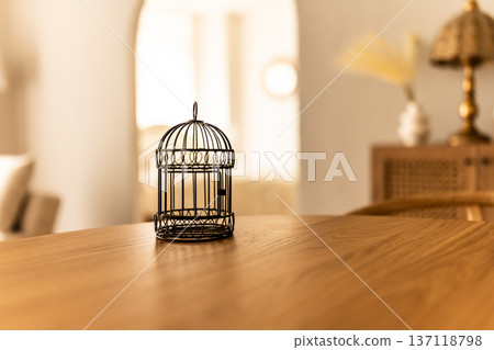 桌上放著一個黑色鳥籠。 桌上放著一個黑色鳥籠。 137118798