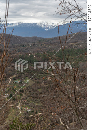 Mountain valley landscape with winding roads and rural houses viewed from Anacopia fortress in Abkhazia with snowcapped peaks in background, Scenic panorama suitable for travel marketing Mountain valley landscape with winding roads and rural houses viewed from Anacopia fortress in Abkhazia with snowcapped peaks in background, Scenic panorama suitable for travel marketing 137118802