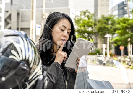 一位騎著大型巡洋艦自行車在橫濱移動的女騎手在平板電腦上確認路線 137119080