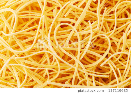 Dry egg noodles forming a tangled yellow background Dry egg noodles forming a tangled yellow background 137119685