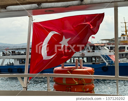 Turkish flag waving on ferry above Bosphorus. National identity, travel, and maritime transport in Istanbul. Turkish flag waving on ferry above Bosphorus. National identity, travel, and maritime transport in Istanbul. 137120202