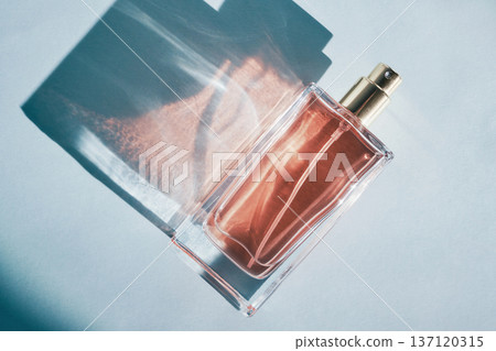Perfume bottle creating aesthetic shadows and light patterns on light background Perfume bottle creating aesthetic shadows and light patterns on light background 137120315