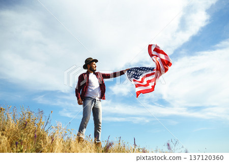 4th of July. American Flag.Patriotic holiday. Traveler with the flag of America. Beautiful sunset light. American style. 137120360