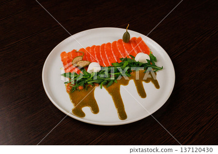 A plate with sliced red fish, bread and greens 137120430