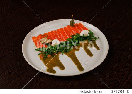 A plate with sliced red fish, bread and greens 137120438