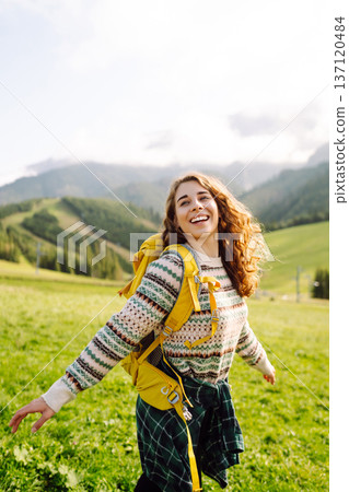 Female tourist with yellow backpack on top of mountain enjoying view of valley. Hiking concept. Female tourist with yellow backpack on top of mountain enjoying view of valley. Hiking concept. 137120484