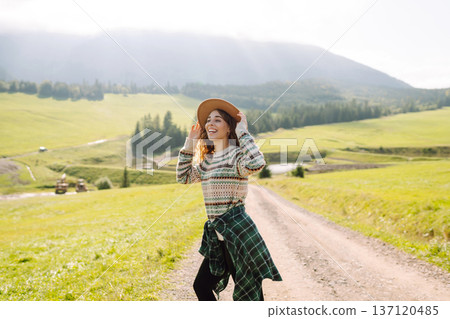 Happy female traveler exploring area in green valley with mountains in background. Concept of nature Happy female traveler exploring area in green valley with mountains in background. Concept of nature 137120485