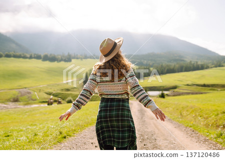 Happy female traveler exploring area in green valley with mountains in background. Concept of nature 137120486