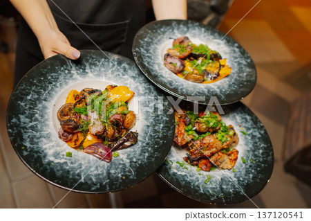 Delicious dishes on plates in the waiter's hand Delicious dishes on plates in the waiter's hand 137120541