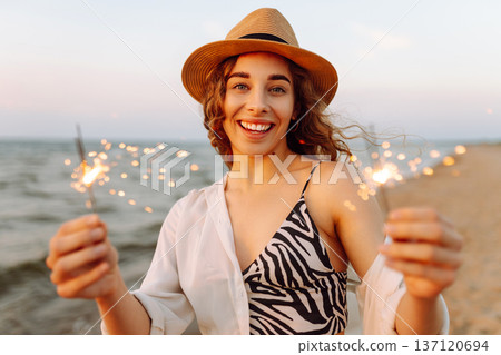 The sparklers in the hands of young woman on the beach. Holidays, vacation, relax, lifestyle concept The sparklers in the hands of young woman on the beach. Holidays, vacation, relax, lifestyle concept 137120694