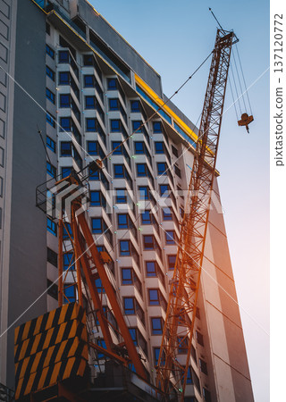 Construction crane by modern building facade at urban real estate development, Lifting tower by high rise architecture, property construction growth 137120772