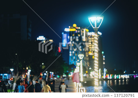 Modern led street lights along promenade alley in night city with reflections, Contemporary illuminated lamps on riverside walkway, glowing urban skyline 137120791