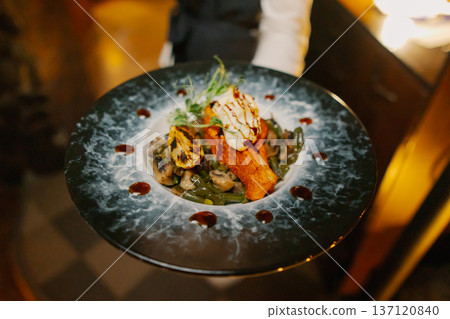 The waiter is serving baked salmon dishes The waiter is serving baked salmon dishes 137120840
