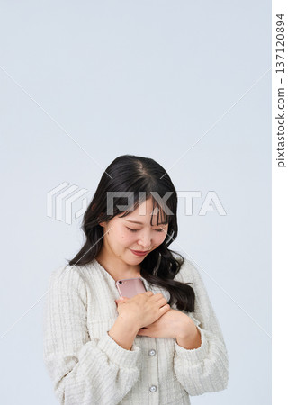 Smiling young woman holding a smartphone Smiling young woman holding a smartphone 137120894