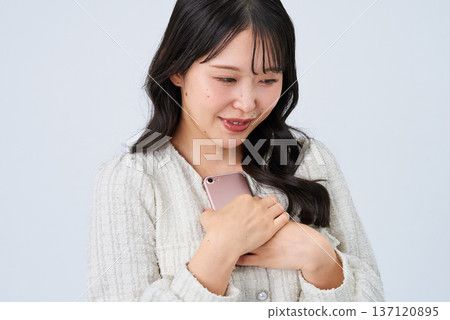 Smiling young woman holding a smartphone Smiling young woman holding a smartphone 137120895