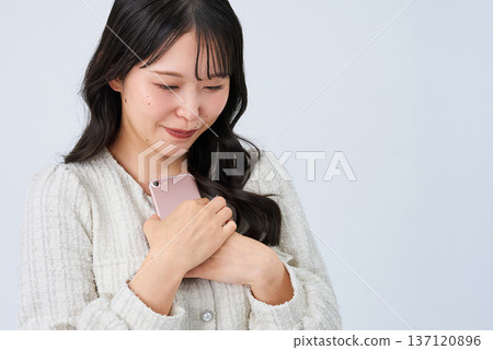Smiling young woman holding a smartphone Smiling young woman holding a smartphone 137120896